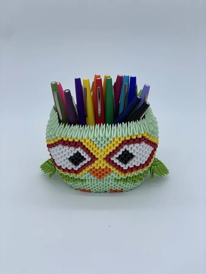 Hibou en origami 3D posé sur un bureau avec des crayons à l'intérieur